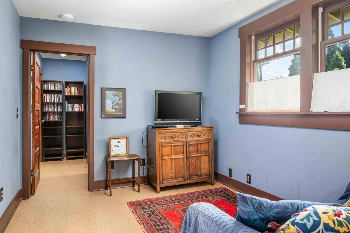A cozy media nook with a wooden cabinet, television, red area rug, and blue couch. The inviting setup is perfect for unwinding with a film or enjoying downtime after a day of exploring.