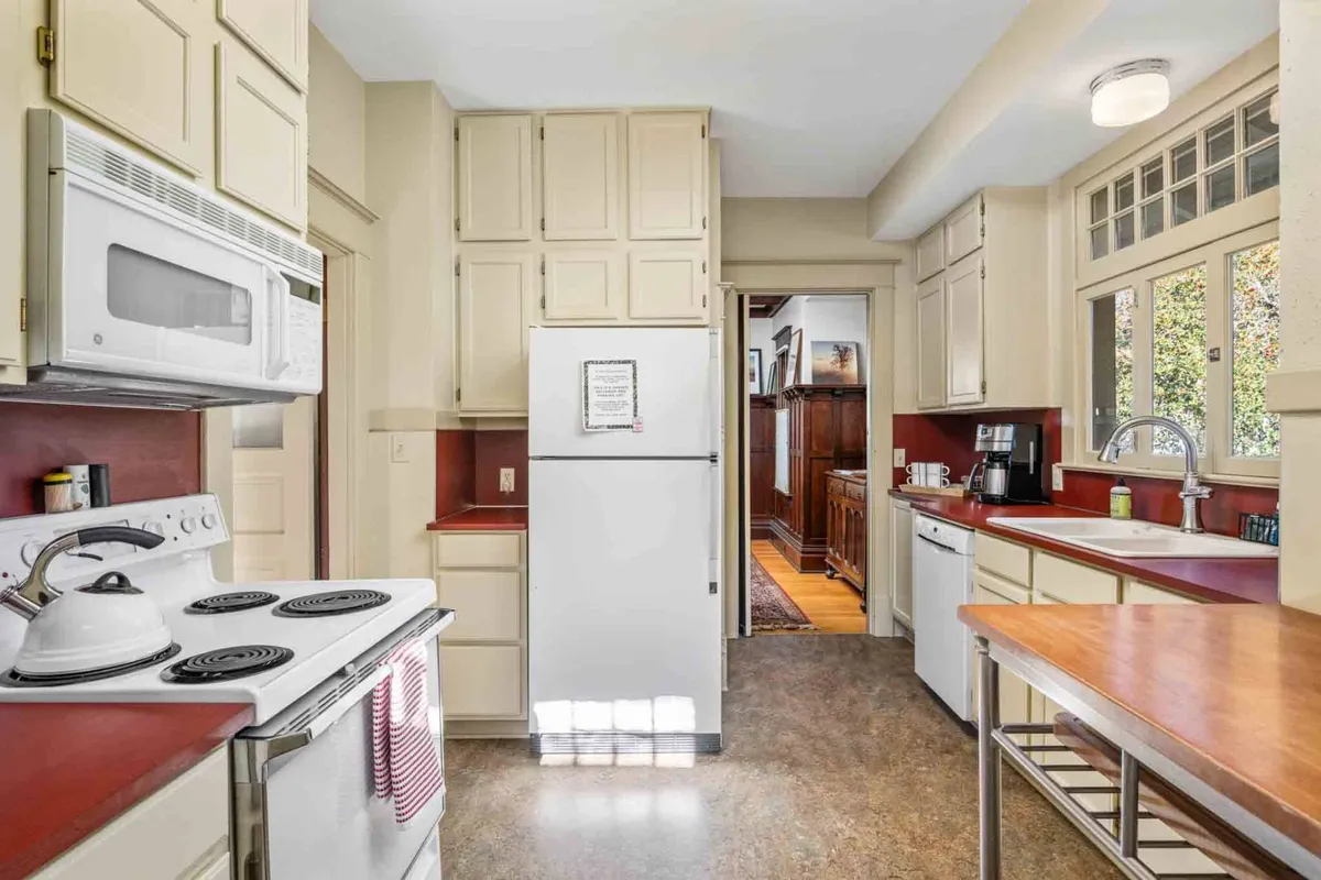 A view of a fully equipped kitchen with a stove, refrigerator, sink, and ample countertop space. The area is styled for both functionality and social interaction, capturing the spirit of cooking, baking, and hosting gatherings.