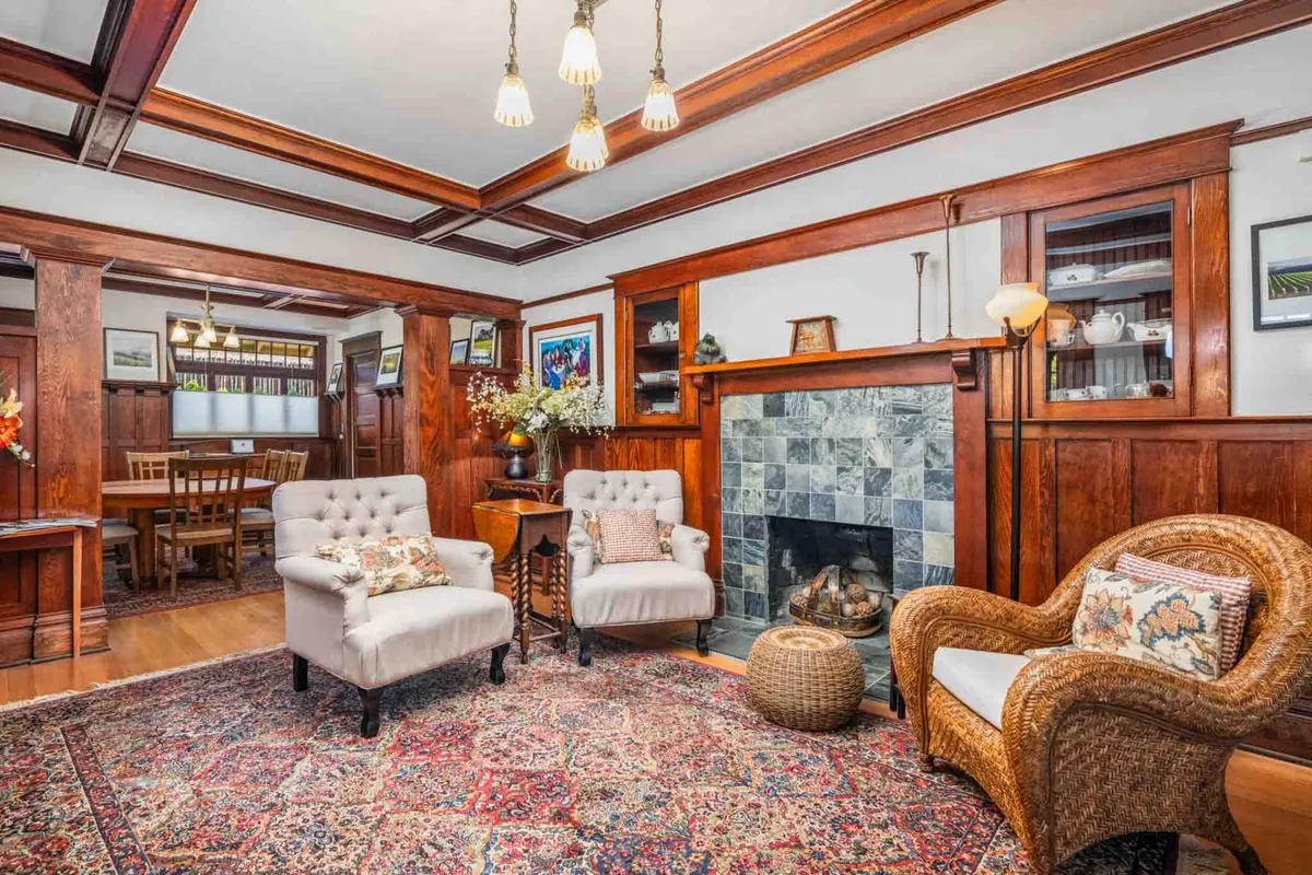 A cozy seating area anchored by a fireplace and decorative rug, with inviting wood paneling creating a warm ambiance. The arrangement encourages relaxation, socializing, or winding down after a productive day.