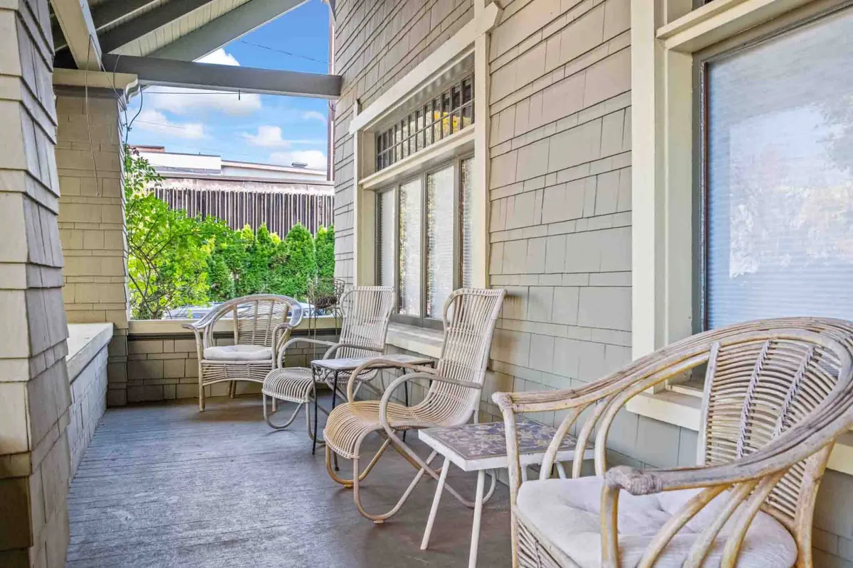 This image features the front porch with its classic rocking chairs and lush greenery, offering a peaceful spot to relax. The view hints at a quiet, friendly neighborhood just beyond the porch.